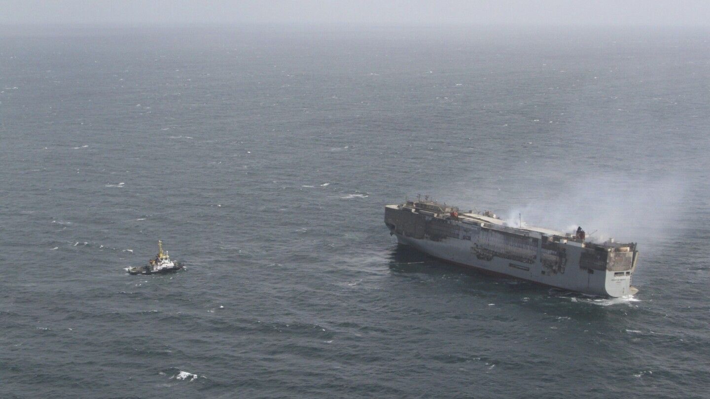 Salvage crews begin towing a burning cargo ship to a new location off the Dutch coast as smoke eases